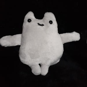 May include: A white plush toy shaped like a cat with black eyes and a small black mouth. The toy has long arms and legs.