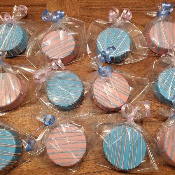 May include: A dozen individually wrapped chocolate-covered cookies decorated with blue and pink stripes. The cookies are tied with ribbons and are ready for a party favor or gift.