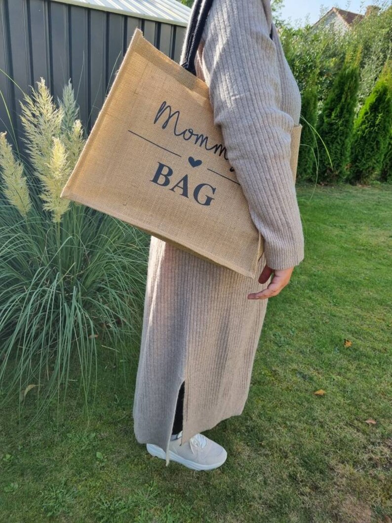 May include: A brown burlap tote bag with black text that reads "Mommy Bag" with a small heart symbol.