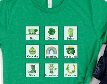 Könnte beinhalten: Ein hellgrünes T-Shirt mit einem Raster aus neun St. Patrick's Day-Symbolen und Beschriftungen: Hat, Clover, Drink, Cupcake, Rainbow, Pot of Gold, Shoe, Leprechaun und Horseshoe. Daneben liegt eine dunkelblaue Jeans mit Used-Look.