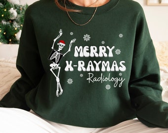 May include: Dark green sweatshirt with the text "MERRY X-RAYMAS Radiology" in white. A skeleton wearing a Santa hat is featured on the left side. White snowflakes are scattered around the text and skeleton.