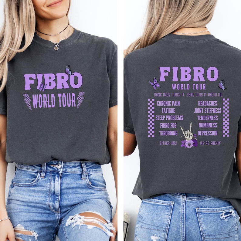 May include: A dark gray t-shirt with a purple graphic that says "FIBRO WORLD TOUR" on the front and a list of symptoms on the back. The graphic includes butterflies and lightning bolts.