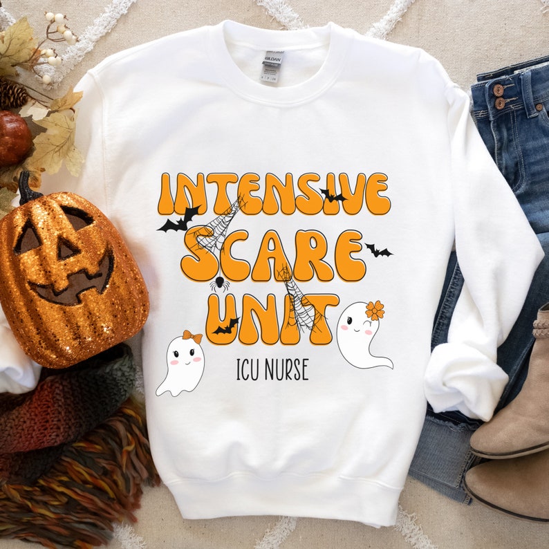 May include: White sweatshirt featuring the words "Intensive Scare Unit" in orange, with bat, spiderweb, and ghost graphics. The text "ICU Nurse" is below the main text. A decorative pumpkin and autumn leaves are in the background.