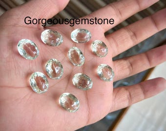 Puede incluir: Una colección de diez piedras preciosas ovaladas de color verde claro. Las piedras preciosas son lisas y translúcidas, con un ligero brillo.