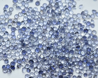 May include: A loose pile of small, round, light blue gemstones. The gemstones are translucent and have a slight sparkle.