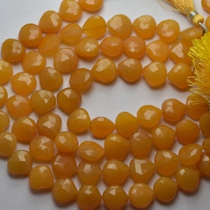 Puede incluir: Una hebra de cuentas de piedra preciosa naranja facetadas. Las cuentas son todas de tamaño y forma aproximadamente iguales, y están enhebradas en un hilo transparente.