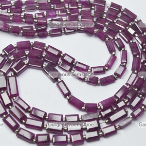 Puede incluir: Primer plano de hilos de piedras preciosas rectangulares de color magenta intenso con espaciadores plateados. Las piedras preciosas facetadas están ensartadas, creando un collar o pulsera. Las cuentas miden aproximadamente 1 cm de largo.