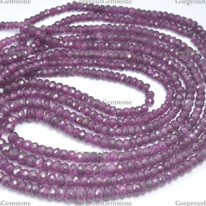 Peut inclure: Un brin de perles de pierres précieuses facettées violettes. Les perles sont petites et rondes, et elles sont enfilées sur un fil transparent. Les perles sont disposées en un motif lâche et fluide.
