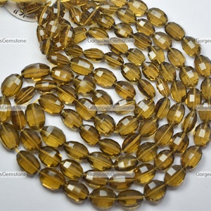 Könnte beinhalten: Eine Strähne aus facettierten, ovalen, braunen Edelsteinperlen. Die Perlen sind durchscheinend und haben einen leicht goldenen Farbton.
