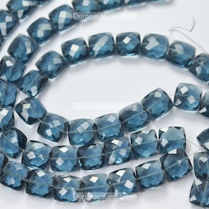 Könnte beinhalten: Eine Strähne aus blauen Topas-Edelsteinkugeln, jede Kugel ist facettiert und hat eine quadratische Form.