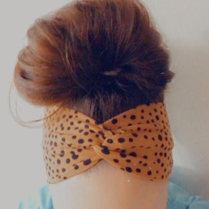 May include: A brown and black patterned headband with a twisted knot design. The headband is made of a soft, stretchy fabric.