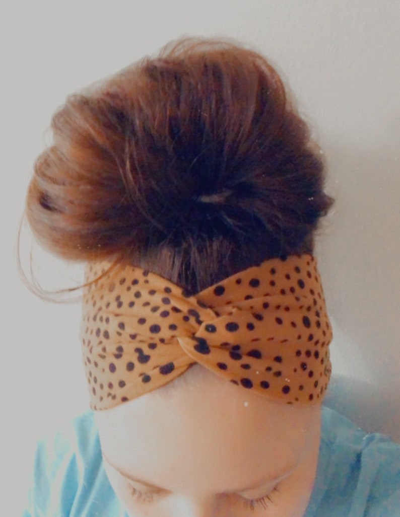 May include: A brown and black patterned headband with a twisted knot design. The headband is made of a soft, stretchy fabric.