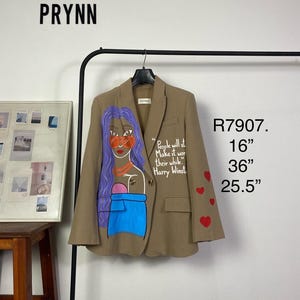 Könnte beinhalten: Beigefarbener Blazer mit einem gemalten Design einer Frau mit lila Haaren, roten Akzenten und blauer Kleidung. Der Blazer hat rote Herzdetails und den Text "People will st Make it wor their while." Der Blazer ist 40,6 cm breit, 91,4 cm lang und 64,8 cm Ärmellänge.
