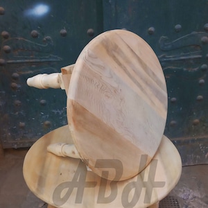 May include: A wooden stool with a round top and three legs. The stool is made of light wood and has a natural finish.