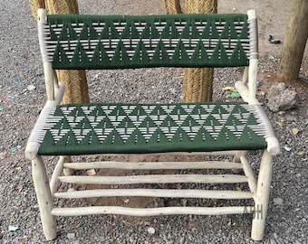 May include: A wooden bench with a green and white woven seat and back. The bench has a simple design with a few slats for support.