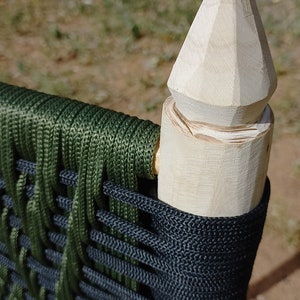 Pode incluir: Close-up de uma cadeira de madeira com um assento tecido verde e preto. A cadeira tem um topo pontiagudo &uacute;nico no poste traseiro.