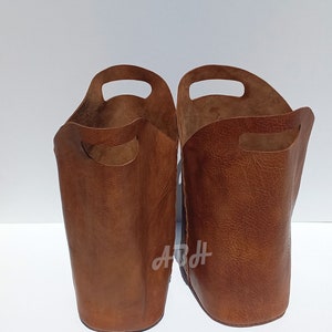 May include: Two brown leather storage baskets with handles. The baskets are empty and have a textured surface.