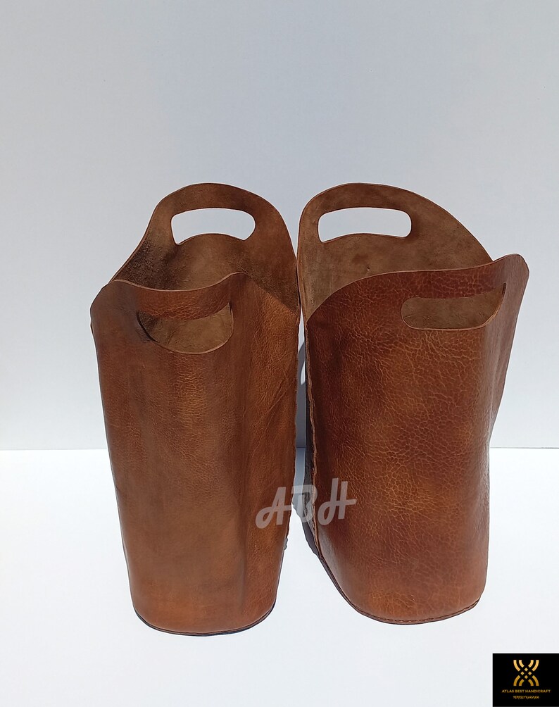 May include: Two brown leather storage baskets with handles. The baskets are empty and have a textured surface.