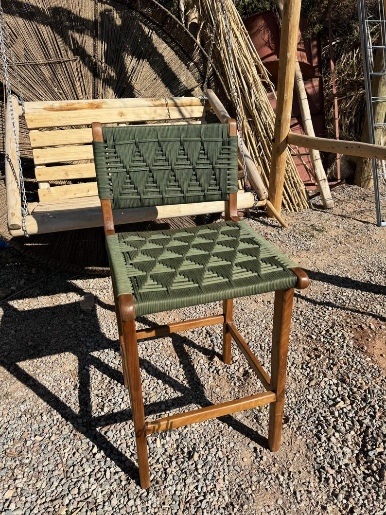 Op de afbeelding: Een groene geweven barkruk met een houten frame. De zitting en rugleuning zijn geweven met een geometrisch patroon.