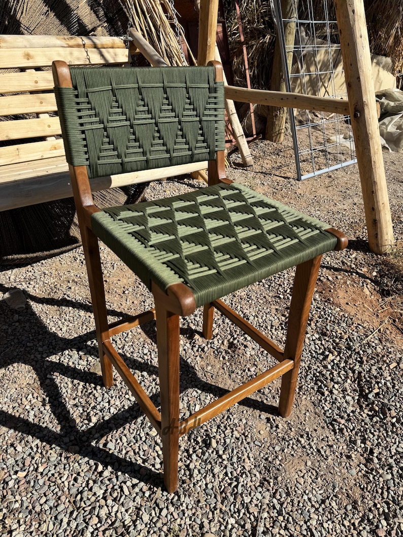 Op de afbeelding: Een houten stoel met een groene geweven zitting en rugleuning. De stoel heeft een eenvoudig ontwerp met een vierkante zitting en een licht gebogen rugleuning.