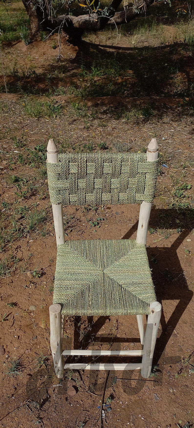 Pode incluir: Uma cadeira tecida com um assento e encosto tecidos de cor verde e natural. A cadeira &eacute; feita de madeira natural e tem um design simples.
