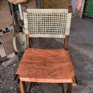 May include: A wooden chair with a woven back and a brown leather seat. The chair is made of dark wood and has a rustic look.