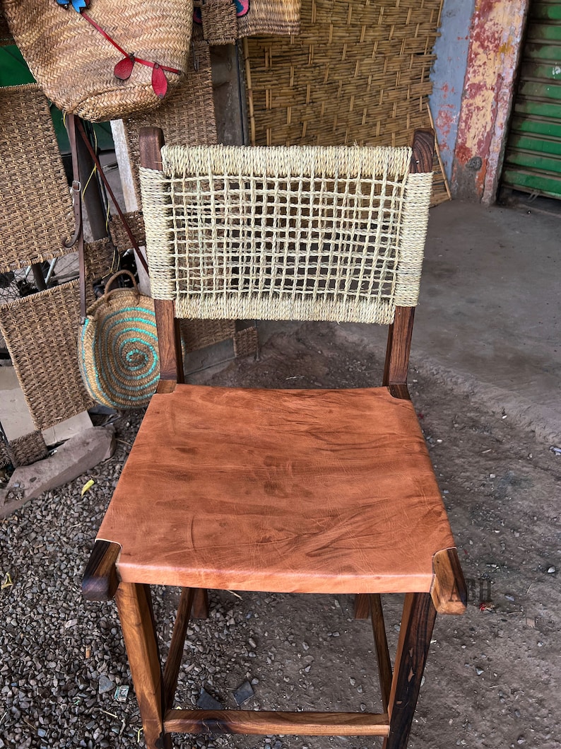 May include: A wooden chair with a woven back and a brown leather seat. The chair is made of dark wood and has a rustic look.
