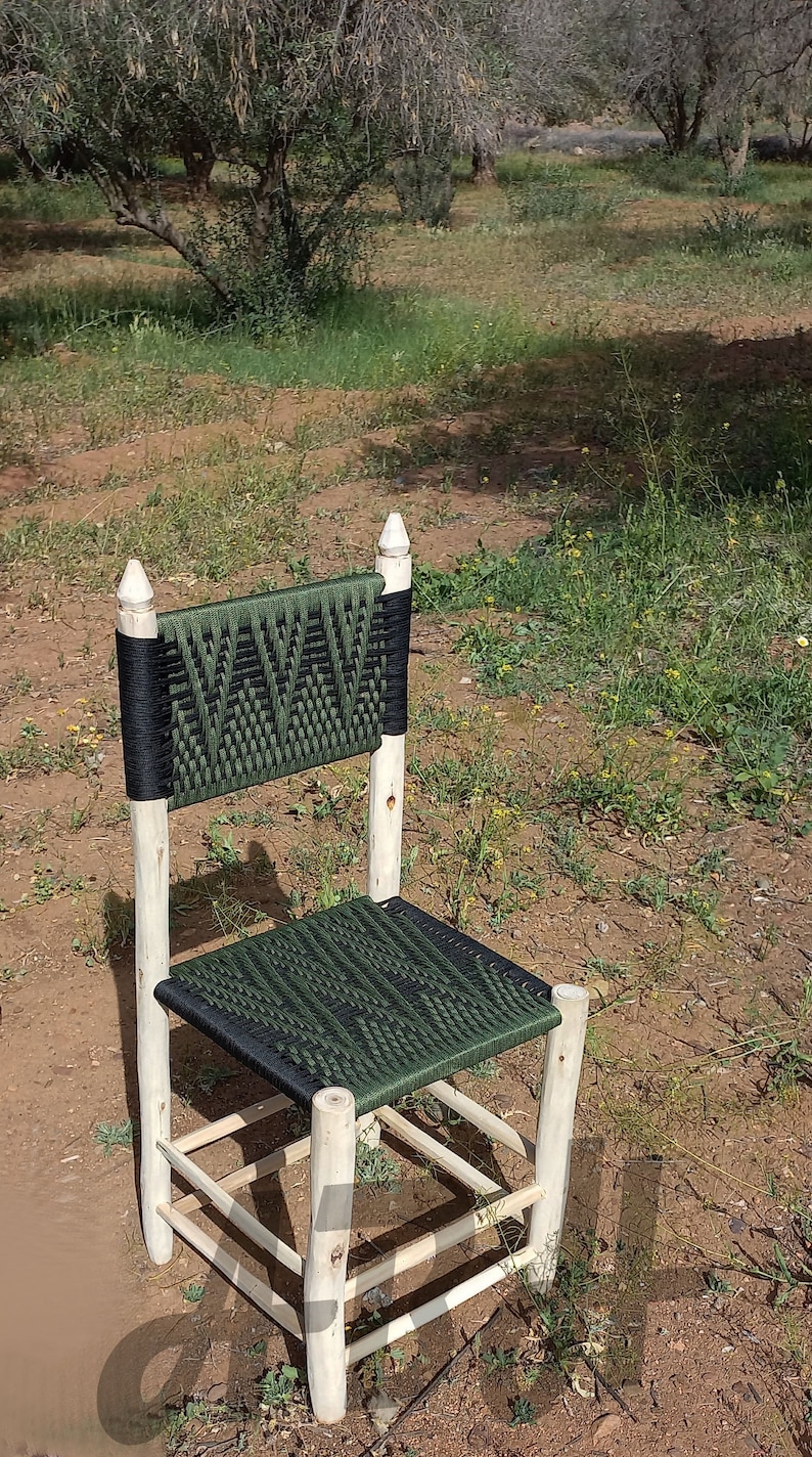 Pode incluir: Uma cadeira de madeira com assento e encosto tecidos em verde e preto. A cadeira tem um design simples com quatro pernas e um assento retangular.
