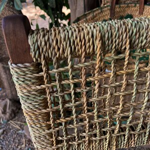 May include: Close-up of a woven chair seat made of natural fibres. The seat is a light brown colour with a woven pattern. The chair is made of wood and has a natural finish.