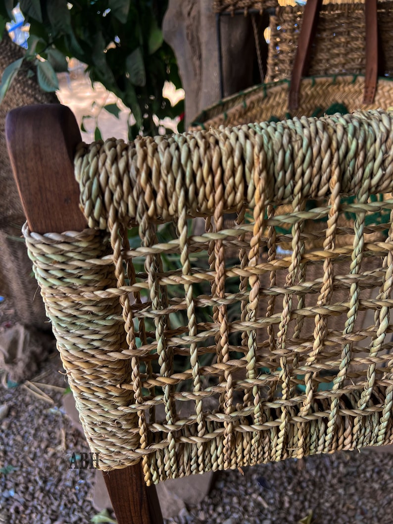 May include: Close-up of a woven chair seat made of natural fibres. The seat is a light brown colour with a woven pattern. The chair is made of wood and has a natural finish.