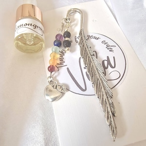 May include: A silver feather bookmark with a rainbow of gemstone beads and a silver apple charm. The bookmark is attached to a small card that says "Thank you for your order Vida".