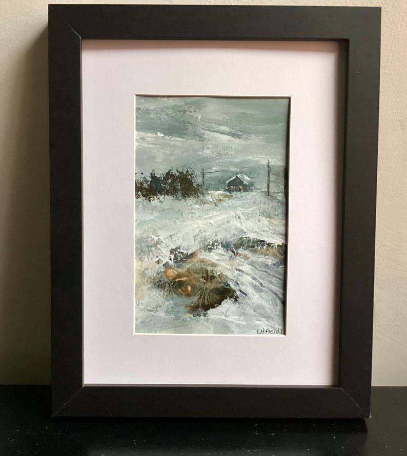 Op de afbeelding: Een ingelijst schilderij met een besneeuwd landschap en een klein bouwwerk in de verte. Het kunstwerk bevat dikke, textuurrijke penseelstreken in tinten wit, grijs en bruin, met de handtekening LH Fields in de rechterbenedenhoek.