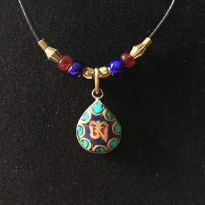 Tibetan style pendant with Buddhist motifs on leather cord
