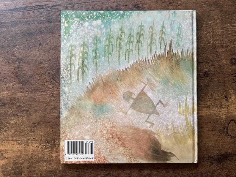 May include: A hardcover book back cover featuring a watercolor illustration of a stylized figure running through a field of tall grass and corn stalks. The artwork uses muted green, brown, and white tones. A barcode and ISBN 0-590-45391-2 are visible.