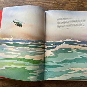 Op de afbeelding: Een open boek met een aquarelillustratie van een groene helikopter die boven een onrustige oceaan met witgekuifde golven vliegt. De rechterpagina bevat gedrukte tekst over een verdwenen onderzee&euml;r in de Barracuda-driehoek.