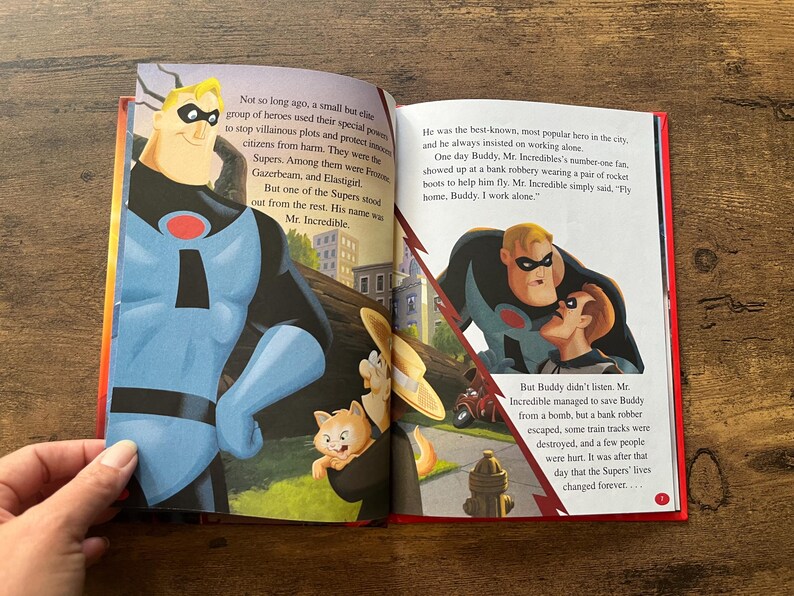 May include: An open children's storybook featuring illustrations of Mr. Incredible from The Incredibles. The left page shows Mr. Incredible standing tall, while the right page depicts him with Buddy. The text narrates the story of the superhero.