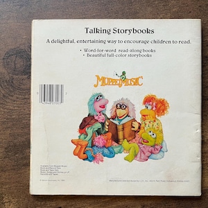 May include: A white back cover of a Talking Storybooks book featuring the Muppet Music logo and a colorful illustration of various Muppet characters. The text includes the title, a description of the read-along books, and a barcode.