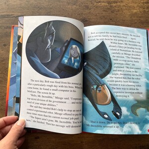 May include: An open children's storybook featuring The Incredibles. The left page shows a character looking at a tablet screen with a woman's face. The right page displays a black robotic vehicle flying over clouds with printed English text.