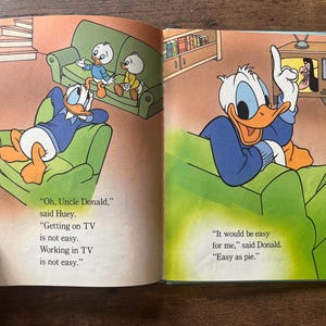 May include: An open children's book page featuring Donald Duck and his nephews in a living room. The text reads: Oh, Uncle Donald, Getting on TV is not easy. Working in TV is not easy. It would be easy for me, said Donald. Easy as pie.