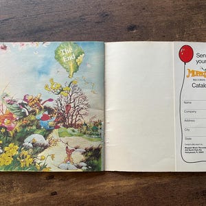 May include: An open book featuring a colorful illustration of Muppet characters on a grassy hill with the text The End on the left page. The right page contains a white form with a red balloon graphic and the text Send for your free Muppet Music Records & Tapes Catalogue with blank lines for contact information.