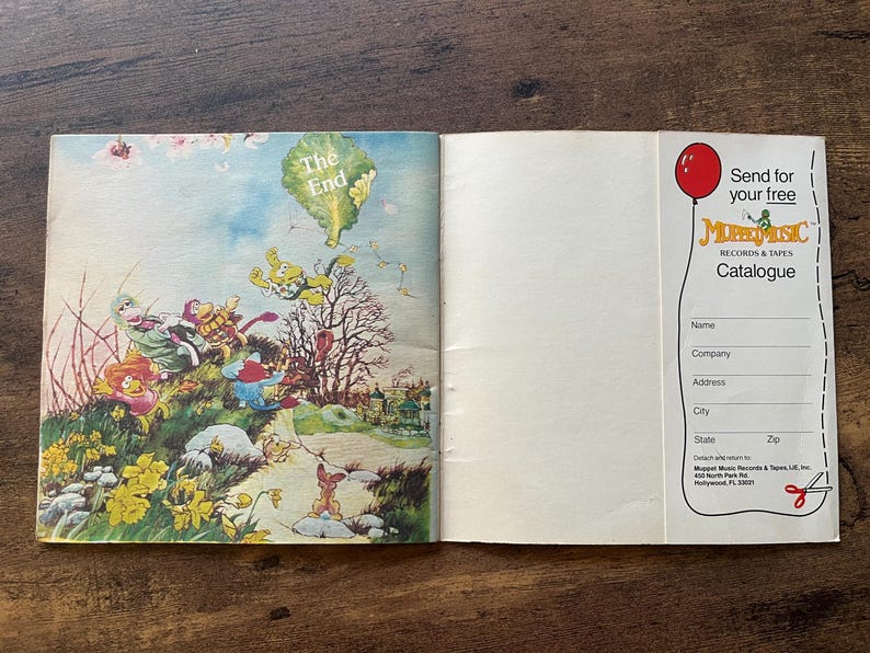 May include: An open book featuring a colorful illustration of Muppet characters on a grassy hill with the text The End on the left page. The right page contains a white form with a red balloon graphic and the text Send for your free Muppet Music Records & Tapes Catalogue with blank lines for contact information.