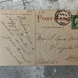 May include: A vintage postcard with a floral design. The postcard is addressed to Miss Clara Murlin in Crystal Falls, Michigan. The postcard has a 1-cent stamp from the United States Post Office dated April 9, 1911.