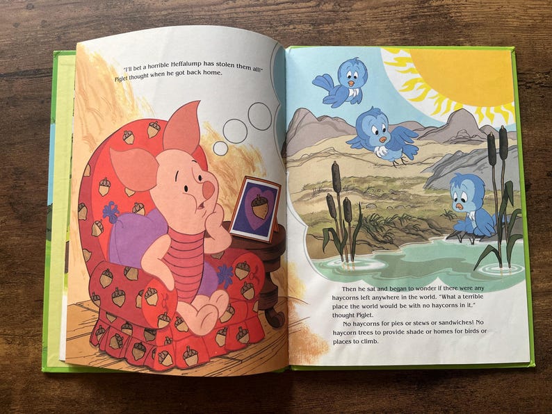 Puede incluir: Un libro infantil abierto que muestra a Piglet sentado en un sill&oacute;n rojo con estampado de bellotas. La p&aacute;gina izquierda muestra a Piglet pensando, mientras que la derecha ilustra un paisaje con p&aacute;jaros azules, un estanque y juncos bajo un sol amarillo brillante.