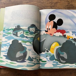 Op de afbeelding: Een open kinderboek met een kleurrijke illustratie van Mickey Mouse in een grijze onderzee&euml;r, omringd door donkergekleurde duikers in het water. De tekst op de linkerpagina beschrijft hoe Mickey uit de onderzee&euml;r klimt.