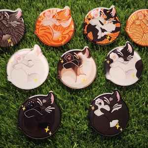 以下が含まれることがあります： 9つの丸い猫をテーマにしたステッカーのコレクション。各ステッカーは、茶色、オレンジ、黒、白など、さまざまな色の眠っている猫を特徴としています。ステッカーは黄色の星のアクセントで装飾され、緑色の表面に配置されています。