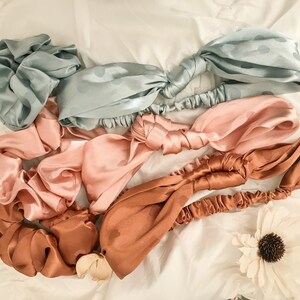 May include: Four satin headbands in different colors: light blue, pink, brown, and a darker brown. Each headband has a polka dot pattern and is tied in a knot.