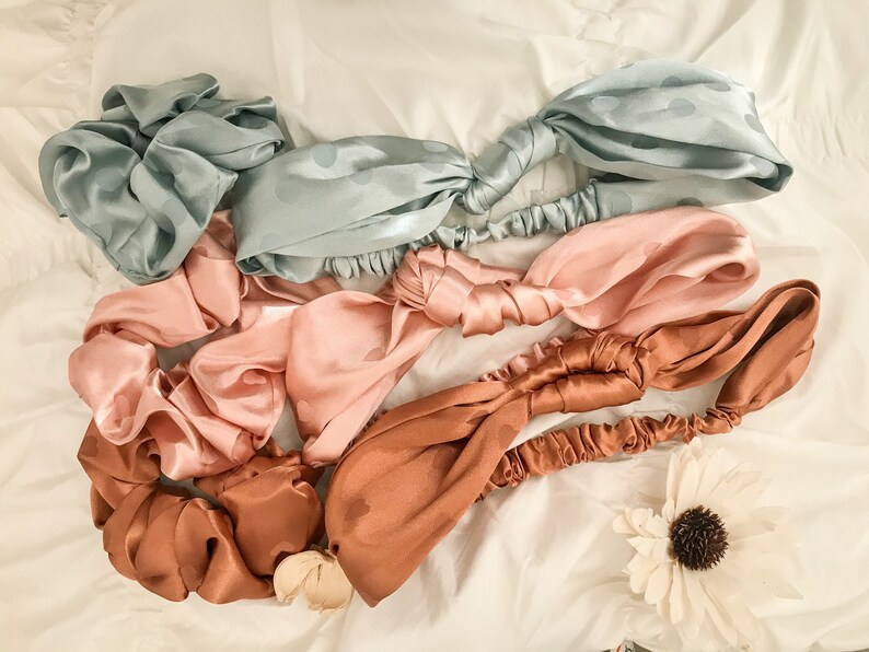 May include: Four satin headbands in different colors: light blue, pink, brown, and a darker brown. Each headband has a polka dot pattern and is tied in a knot.