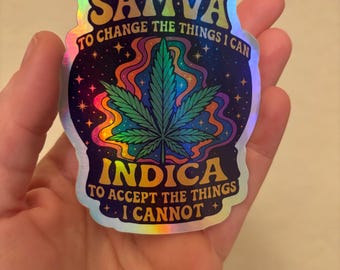 May include: Holographic sticker with the words "Sativa" and "Indica" in gold lettering. The sticker features a cannabis leaf and colorful psychedelic swirls. Text reads "To change the things I can" and "To accept the things I cannot."