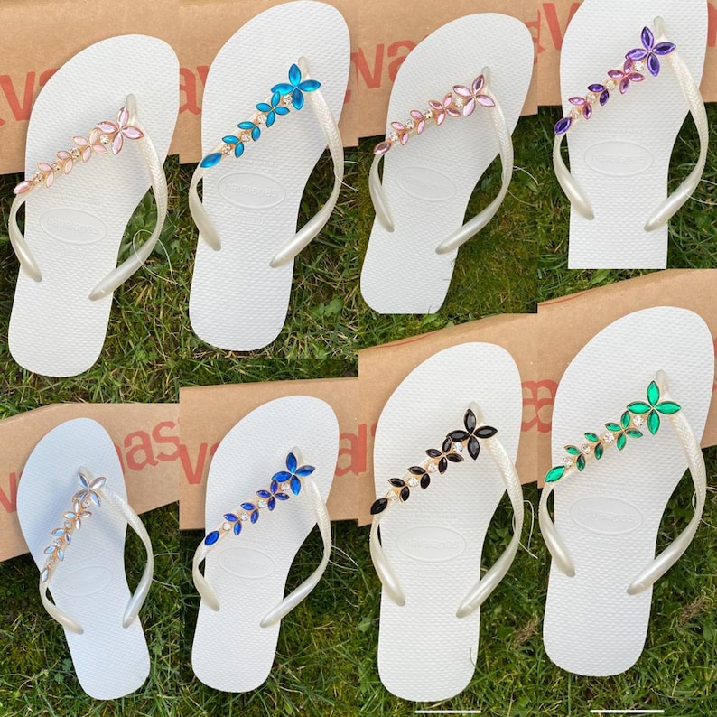 May include: A white ceramic mug with a black handle and the text "But First, Coffee" in a bold, black font. The mug is set against a blurred background, suggesting a cosy setting.