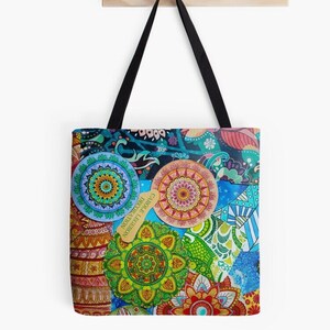 Puede incluir: Una bolsa de tela colorida con un diseño de mandala. La bolsa está hecha de lona y tiene un asa negra. El diseño de mandala está hecho de varios colores, incluyendo rojo, naranja, amarillo, verde, azul y morado. La bolsa tiene el texto "CAROLINE LEBERTHON DECORATION" en ella.